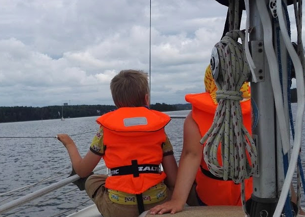 Kaksi lasta liivit päällä veneen kannella